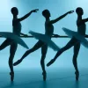 Three ballerinas in silhouette wear tutus with one arm stretched in front of them and one leg pointed behind them.